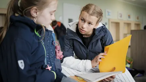 Zwei Schülerinnen schauen zusammen in ein Heft
