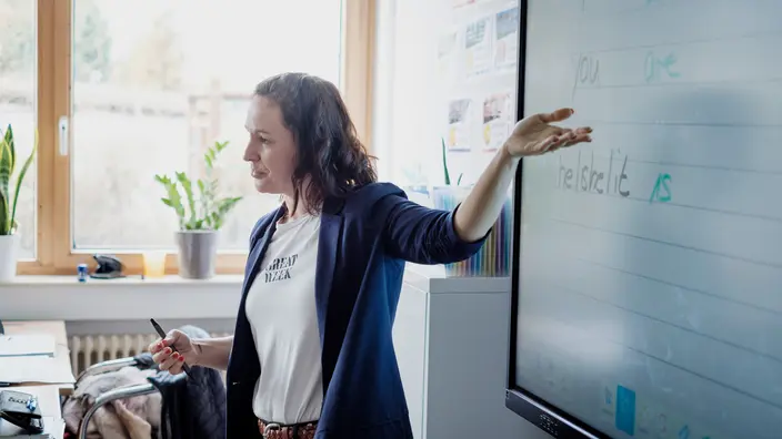 Eine Lehrerin zeigt auf die Tafel