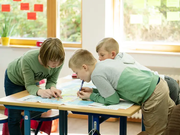 Mehrere Schüler arbeiten zusammen an einer Weltkarte